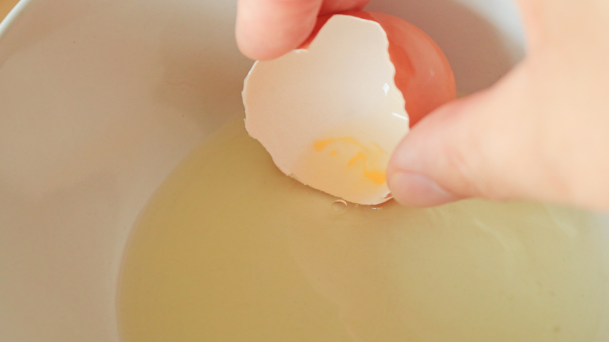 Using an eggshell to scoop up yolk from egg whites.